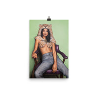 An 12 inch by 18 inch museum quality liana z weber artworks original poster. beautiful and affordable wall art of a strong female sitting, leaning back in a purple chair against a soft light green background. She is wearing a lion headdress and is staring boldly at the viewer. She is the female version of the legendary mythological character Hercules. A strong and badass woman that needs no one and is self assured.
